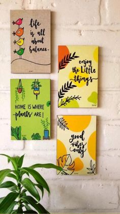 three canvases with quotes on them hang on the wall next to a potted plant