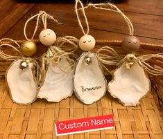 three ceramic angel ornaments with personalized names on them sitting in a wicker basket