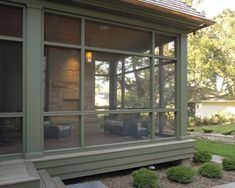 a screened in porch with seating area and stone steps leading up to the front door