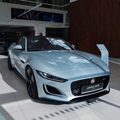 a silver sports car parked in front of a building with two other cars behind it