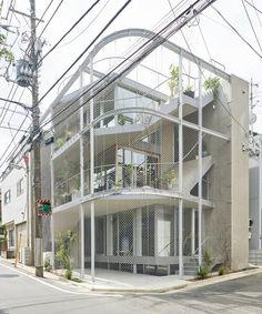 an apartment building with many balconies and plants on the top floor is surrounded by wires