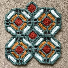 a crocheted flower is shown on the floor in front of a carpeted wall