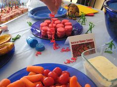 a table topped with blue plates filled with carrots and small cakes covered in frosting