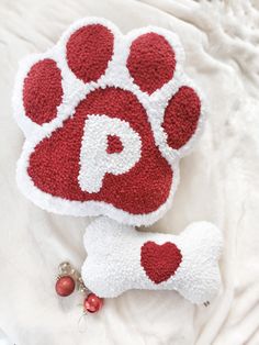 a red and white dog paw pillow next to a christmas ornament on a bed