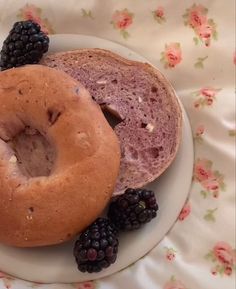 two bagels on a plate with blackberries and raspberries