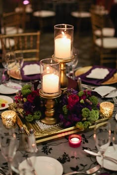 candles are lit on the centerpiece of a table set for an elegant wedding reception