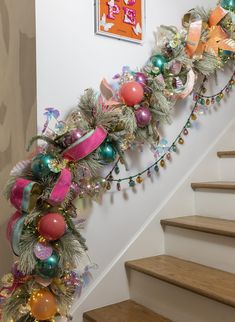 a christmas garland on the wall next to some stairs with ornaments and decorations around it