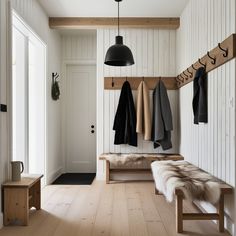 a bench and coat rack in a white room with wood flooring on both sides