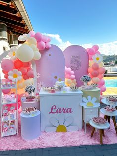 a pink and white dessert table with balloons