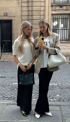 two women standing next to each other holding cell phones