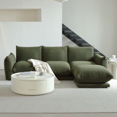 a green couch sitting on top of a white floor next to a stair case in a living room