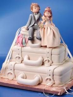 a wedding cake made to look like a train with people sitting on the engine and luggage