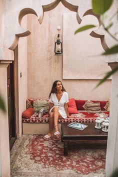 a woman sitting on top of a couch in a living room next to a table