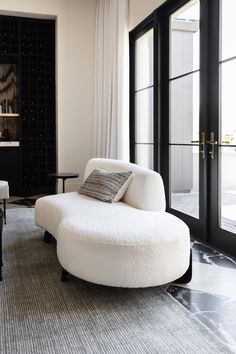 a living room filled with white furniture and black doors leading to an open patio area