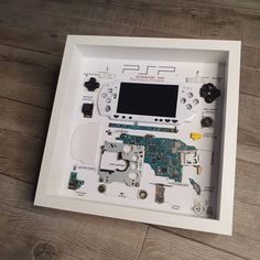 the inside of a white framed display case with various electronic components in it on a wooden floor