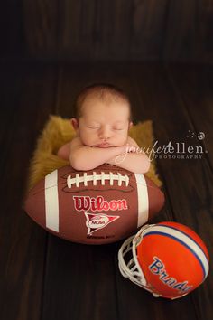 a newborn baby is sleeping on top of a football and next to an orange ball