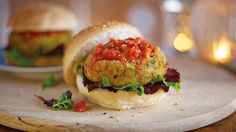 a meatball sandwich with tomato sauce and lettuce on a wooden cutting board