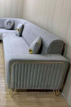 a large gray couch sitting on top of a hard wood floor next to a window