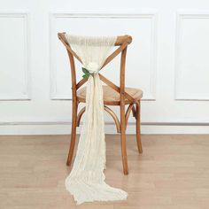 a chair with a white cloth draped over it and a flower on the back of it