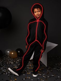 a young boy wearing a black and red light up costume standing in front of confetti