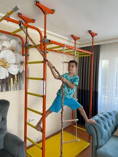 a young boy standing on a ladder in a living room next to a blue couch