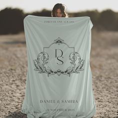 a woman holding up a blanket with the letter b on it in front of her