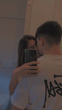 a man and woman taking a selfie in front of a bathroom mirror with their cell phone