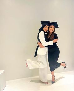 two women dressed in black and white hugging each other