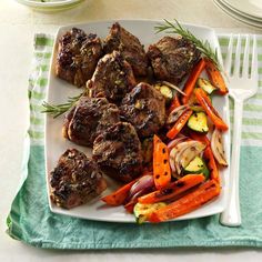 a white plate topped with meat and veggies on top of a green table cloth