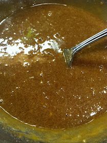 a spoon is stirring some food in a pot with brown liquid on the stove top