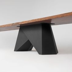 a wooden bench sitting on top of a white floor next to a black object with a wood edge