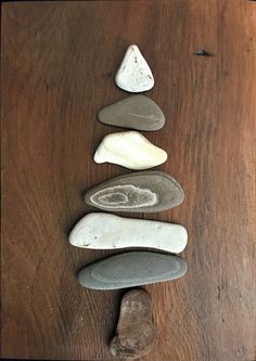 five rocks arranged in the shape of a pyramid on a wooden table with one rock laying next to it