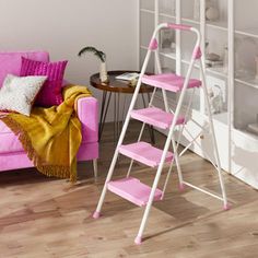 a living room with pink furniture and a white ladder next to a couch in front of a bookshelf