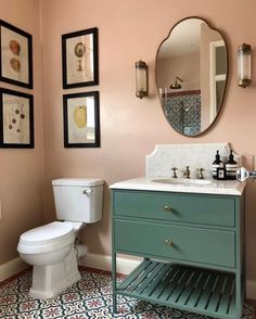 a bathroom with a toilet, sink and pictures on the wall above it's mirror