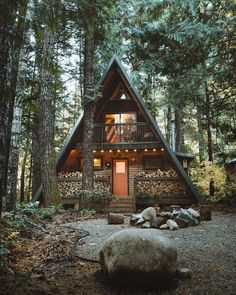 an image of a cabin in the woods with trees and rocks on the ground next to it