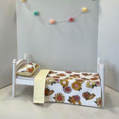 a small white bed sitting next to a wall with colorful balls hanging from it's sides