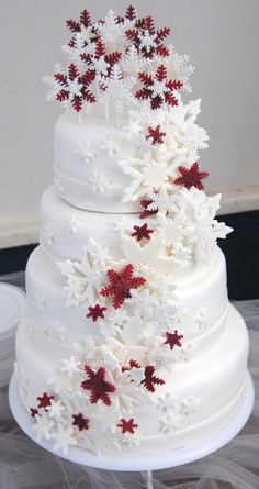 a three tiered white wedding cake with red and white snowflakes on it