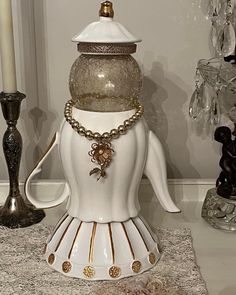 a white vase sitting on top of a table next to a candle and some glass candlesticks