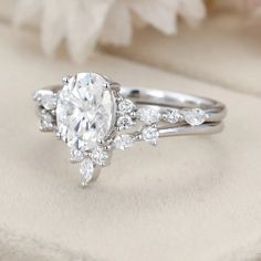 a close up view of a wedding ring with an oval cut diamond surrounded by smaller round diamonds