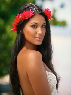 a beautiful young woman with long black hair and red flowers in her hair wearing a white dress