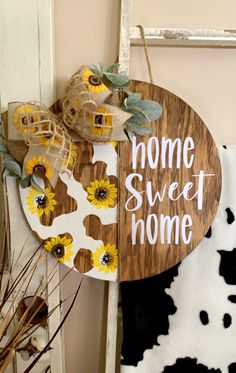 a wooden sign that says home sweet home with sunflowers hanging from the side