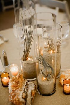 there are candles and sand in vases on the table