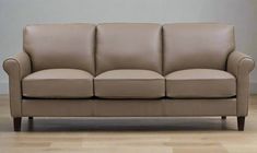 a tan leather couch sitting on top of a hard wood floor