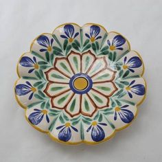 a decorative plate with blue, green and yellow flowers on the rim is shown against a white background