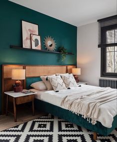 a bedroom with teal walls and white bedding in the corner, along with two lamps on either side of the bed