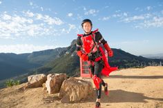 a woman dressed in red and black running on top of a hill next to a phone booth