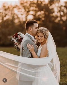 a bride and groom embracing each other in front of the sun at their outdoor wedding