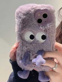 a woman holding a purple stuffed animal in her hands and looking at it's camera