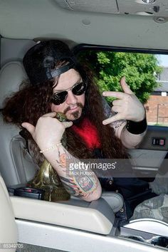 a man with long hair sitting in the back seat of a car and pointing at something