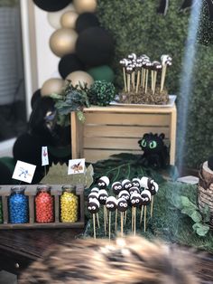 a table topped with cake pops covered in black and white frosting next to a wooden box filled with candy